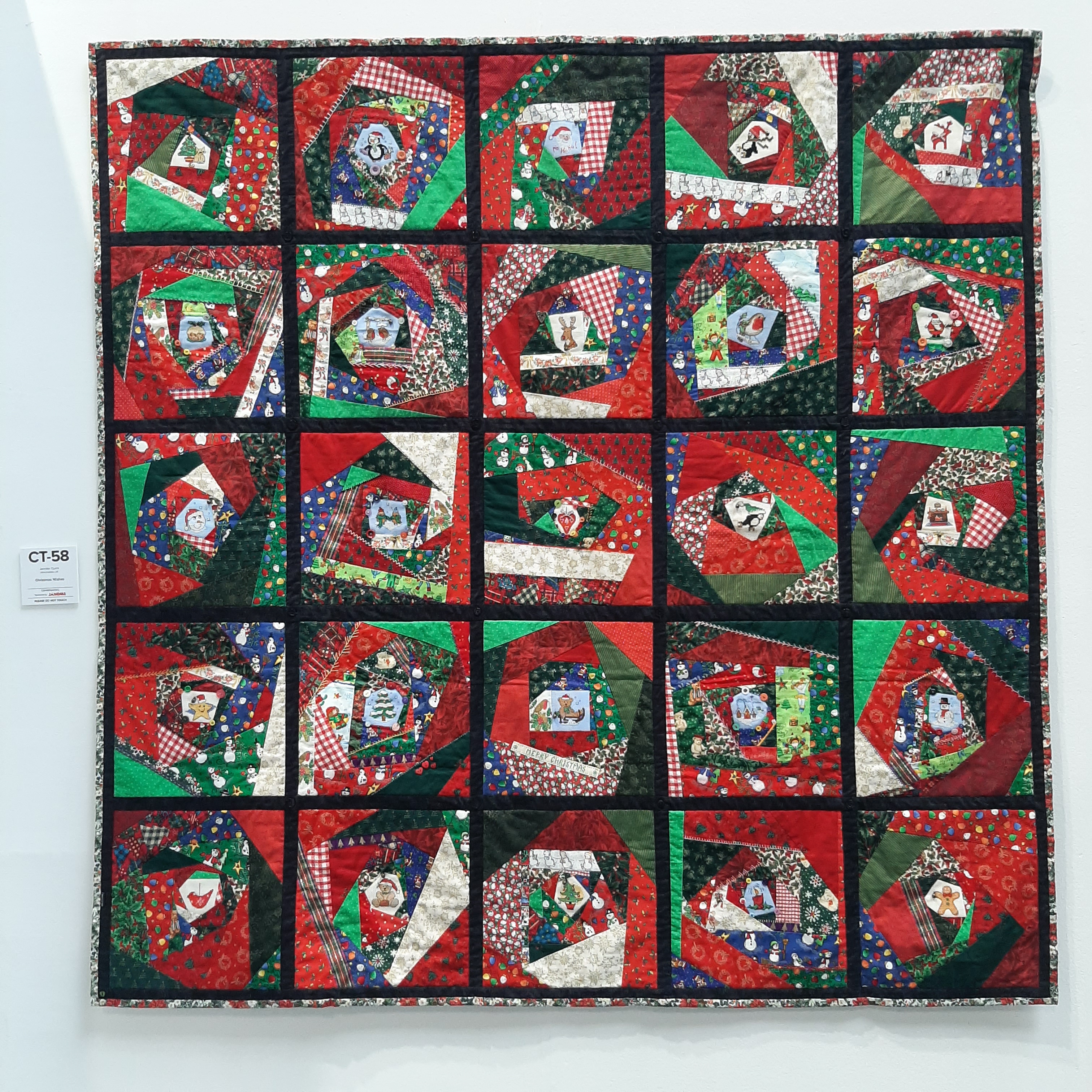 Christmas quilt using red, green and black hung on a gallery wall