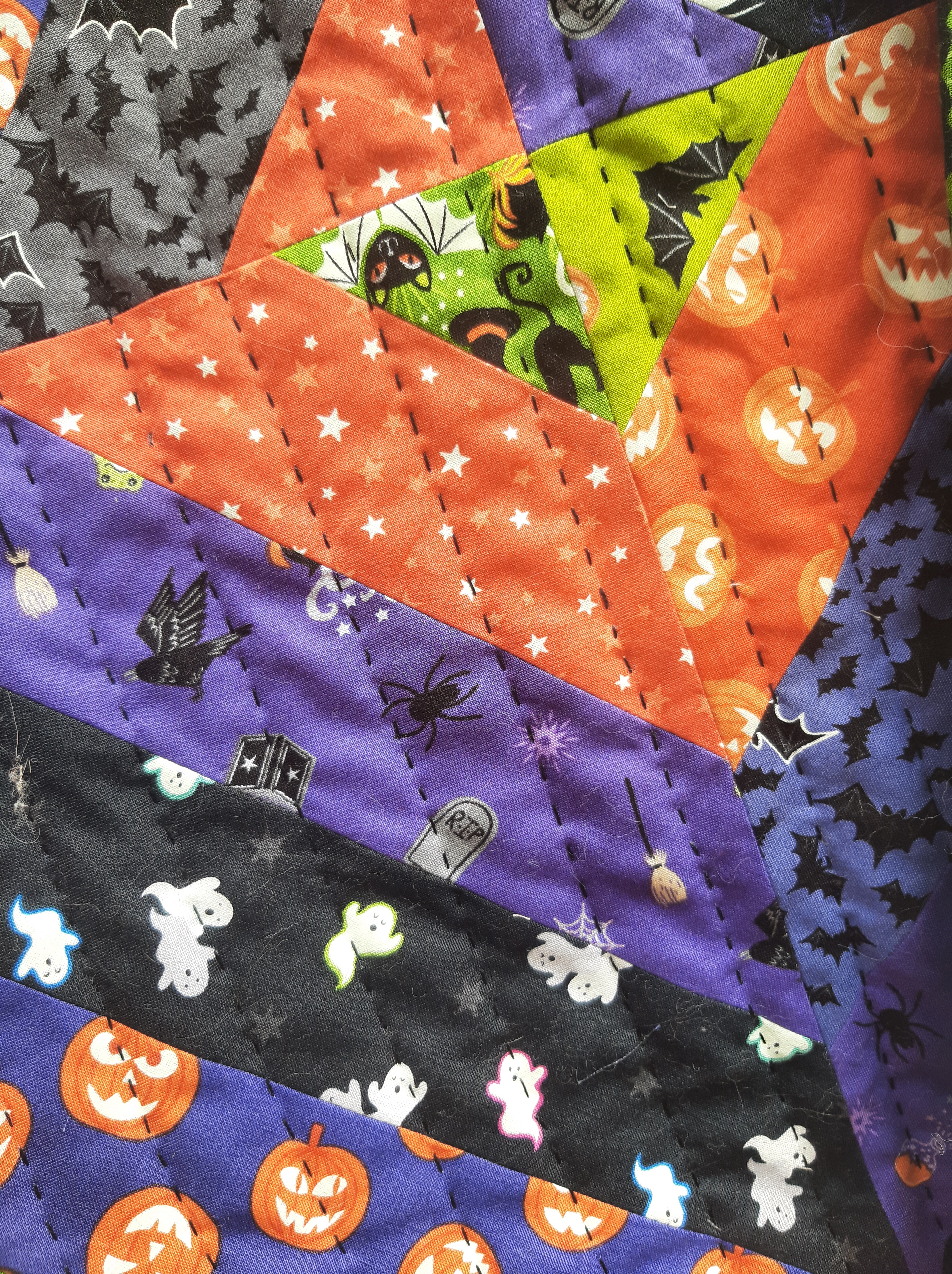 Close-up of various Halloween fabrics stitched together into a quilt using black quilting thread