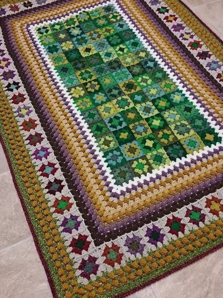 Green and brown crocheted blanket on a floor